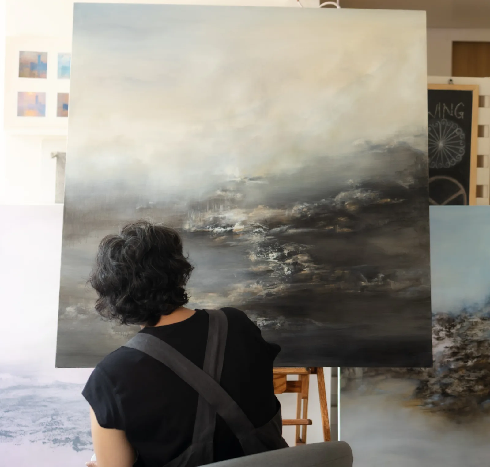 The artist contemplating a large landscape painting in her studio